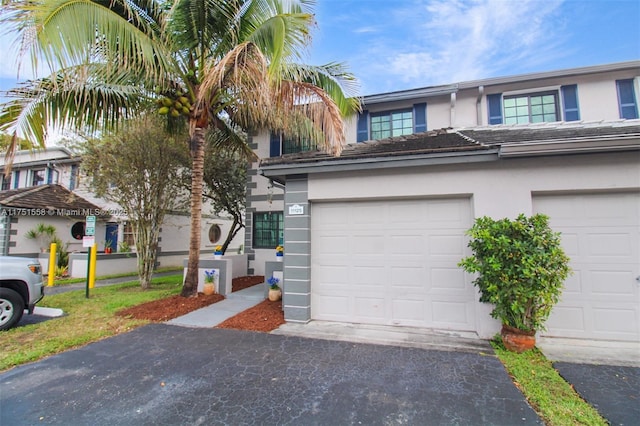 multi unit property with a garage, driveway, and stucco siding