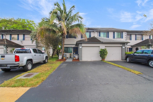 multi unit property with driveway, an attached garage, and stucco siding