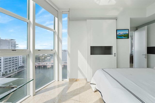 bedroom with a wall of windows, a water view, and granite finish floor