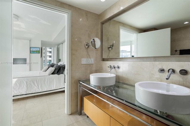 bathroom featuring double vanity, ensuite bath, tile walls, and a sink