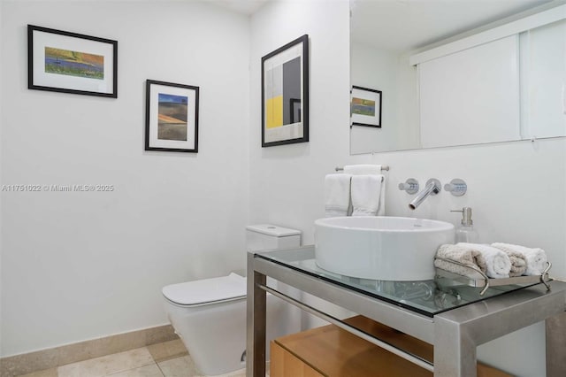 half bathroom featuring tile patterned flooring, baseboards, vanity, and toilet