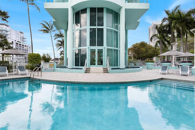 community pool featuring a patio area, fence, and french doors