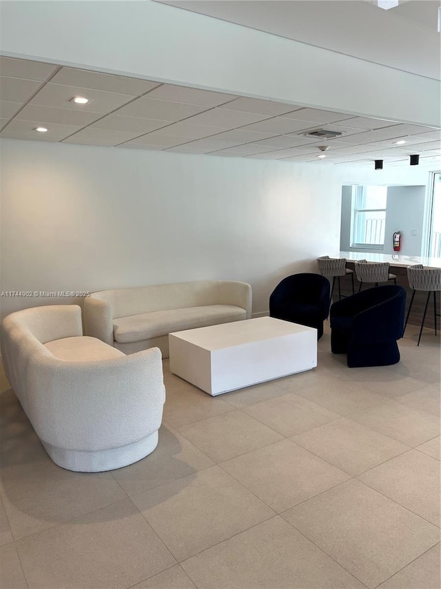 living room with a drop ceiling, visible vents, and recessed lighting