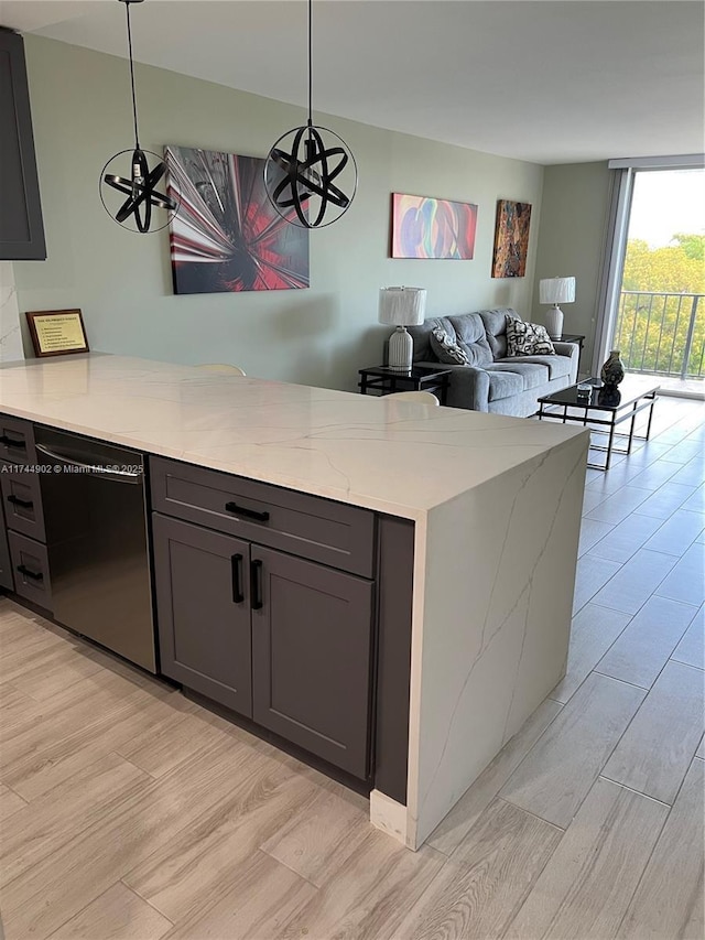 kitchen featuring light stone counters, black dishwasher, and hanging light fixtures