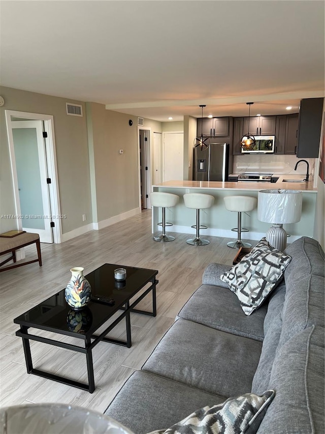 living room featuring light wood-type flooring, visible vents, and baseboards