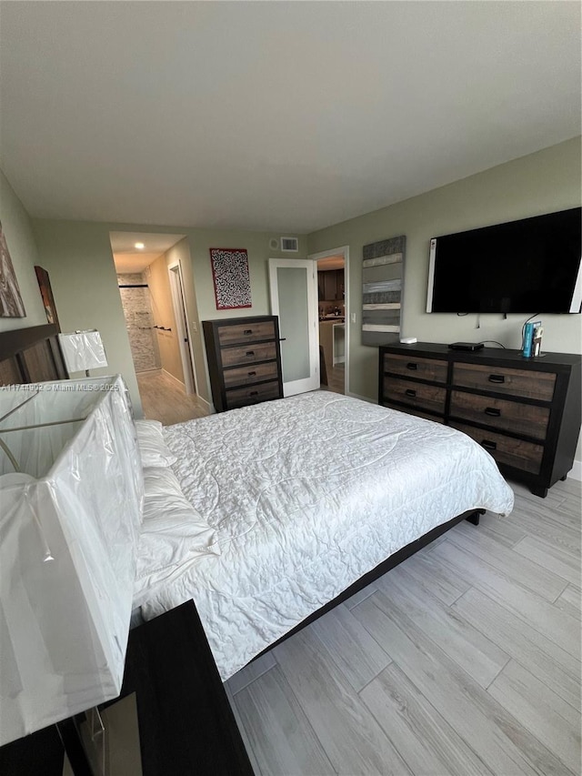 bedroom with light wood finished floors and visible vents