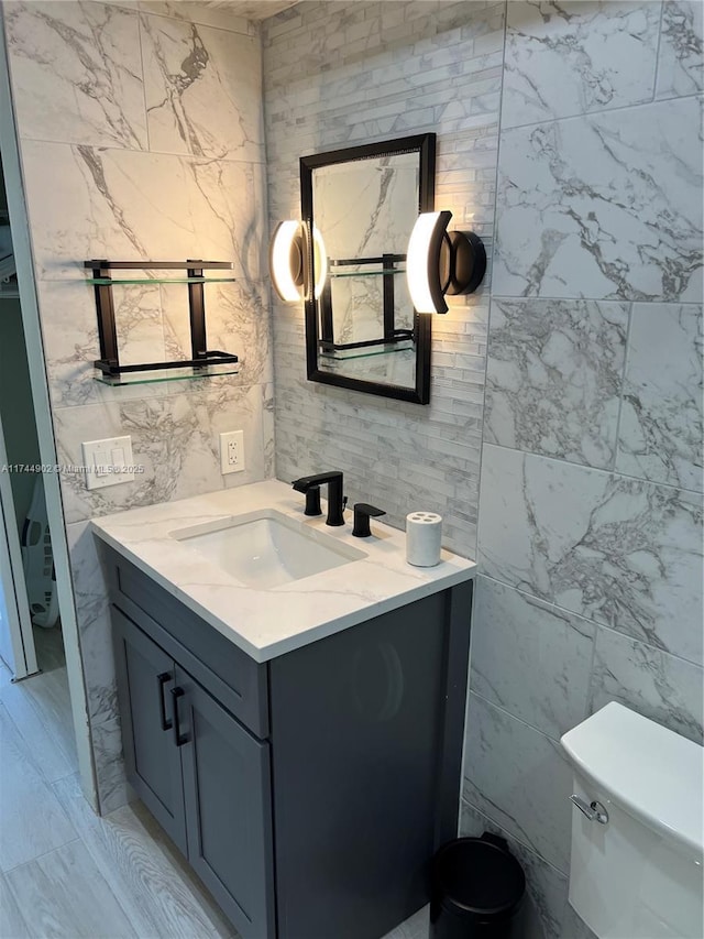 half bath with toilet, tile walls, and vanity