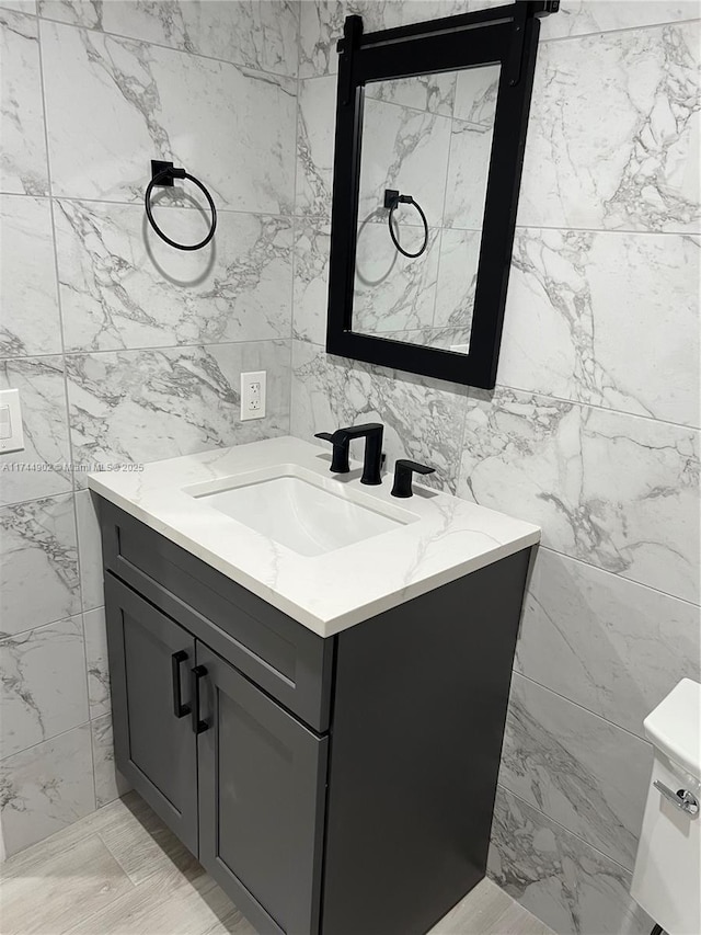 bathroom featuring toilet, vanity, and tile walls