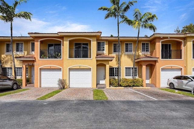 view of front of house featuring driveway, a balcony, an attached garage, and stucco siding