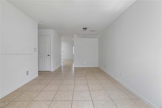 spare room with baseboards and light tile patterned floors