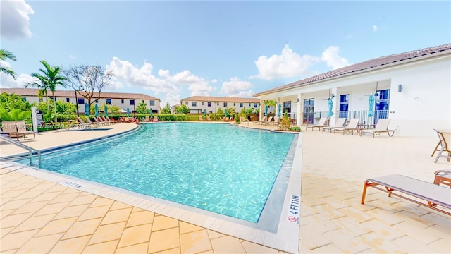 community pool with a patio area and fence