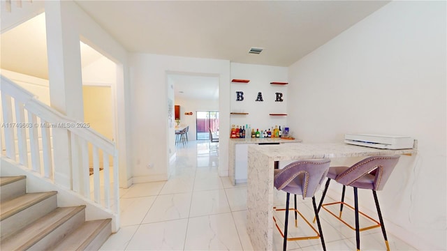 bar featuring marble finish floor, visible vents, stairway, and baseboards