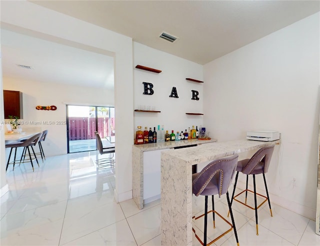 bar with marble finish floor, visible vents, baseboards, and a dry bar