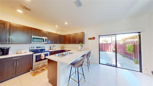 kitchen featuring a breakfast bar, a sink, visible vents, light countertops, and appliances with stainless steel finishes