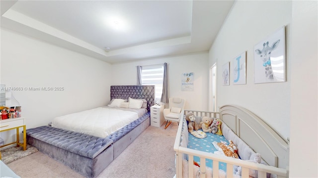 bedroom with a raised ceiling and light colored carpet