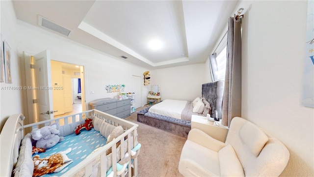 bedroom with light carpet, visible vents, and a tray ceiling