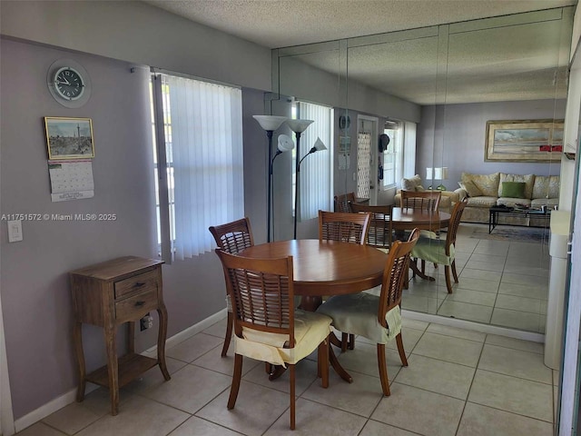 dining space featuring a textured ceiling, baseboards, and light tile patterned floors