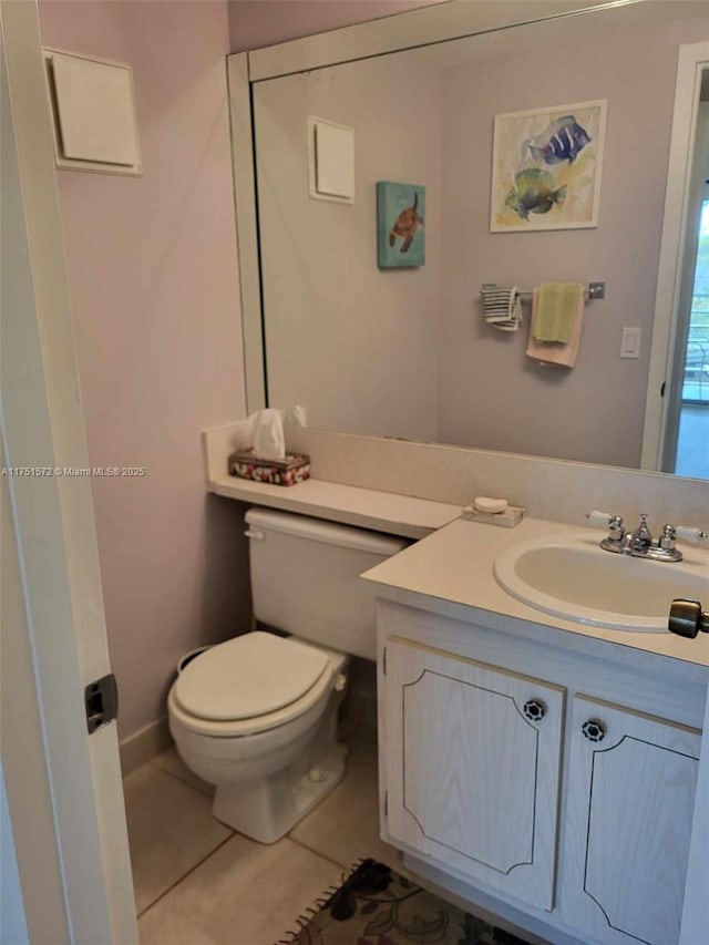 half bath with toilet, tile patterned flooring, and vanity