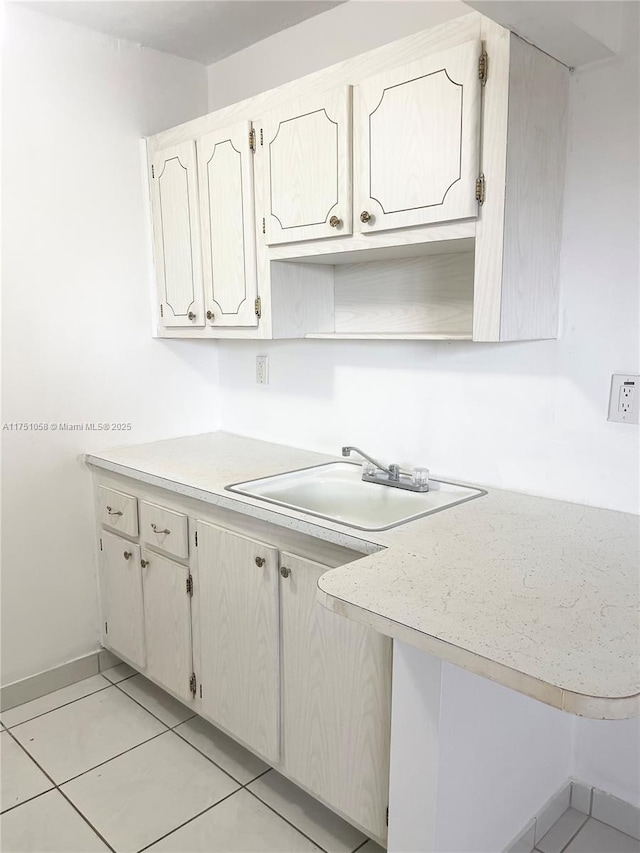 kitchen featuring light tile patterned floors, baseboards, light countertops, open shelves, and a sink