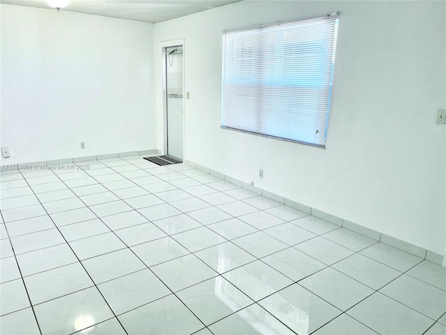 empty room with light tile patterned floors and baseboards