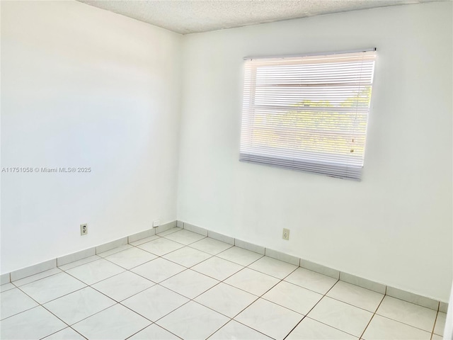 spare room with a textured ceiling and baseboards