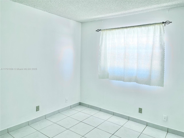 unfurnished room featuring a textured ceiling, baseboards, and light tile patterned floors