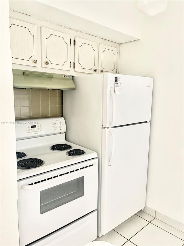 kitchen with white appliances, light tile patterned flooring, and under cabinet range hood