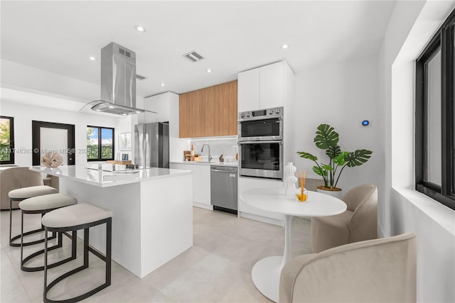 kitchen with a center island, stainless steel appliances, light countertops, white cabinets, and modern cabinets