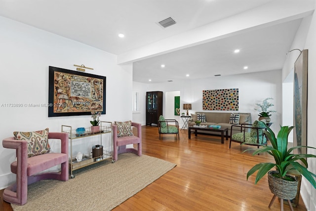 living room with recessed lighting, visible vents, and wood finished floors