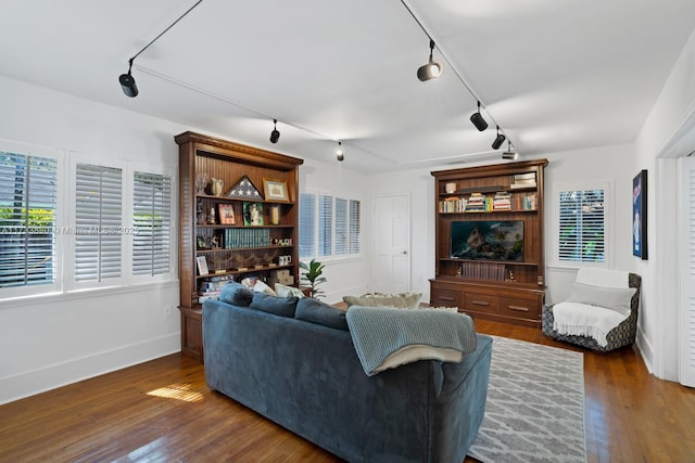 living room featuring dark wood finished floors, rail lighting, and baseboards