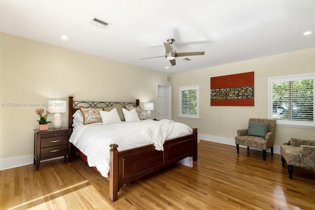 bedroom with wood finished floors, visible vents, and baseboards