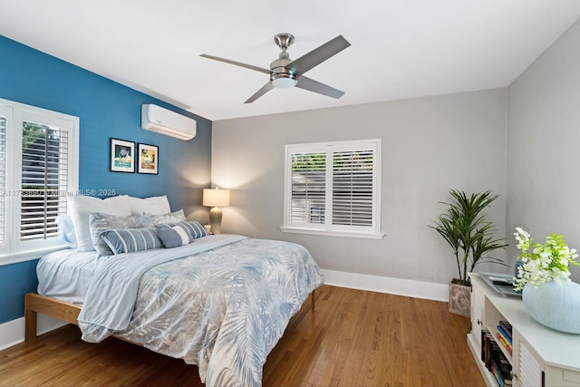 bedroom with a wall mounted AC, wood finished floors, a ceiling fan, and baseboards