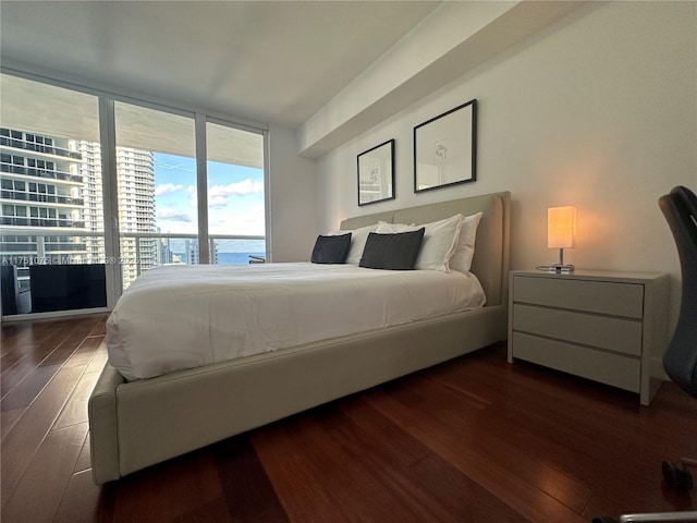 bedroom with access to outside, dark wood-style flooring, a water view, and floor to ceiling windows