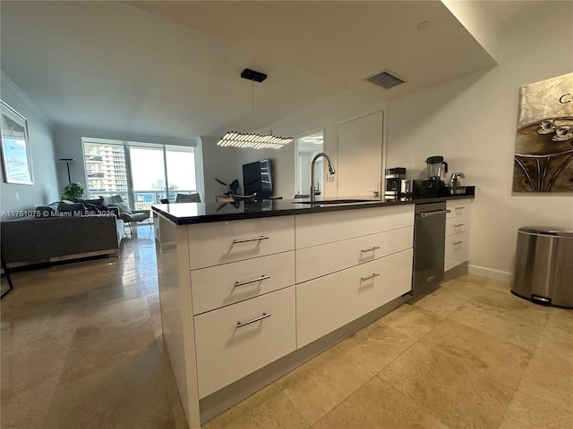 kitchen with dark countertops, open floor plan, decorative light fixtures, white cabinetry, and a sink