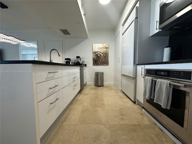 kitchen with visible vents, appliances with stainless steel finishes, white cabinetry, a sink, and baseboards