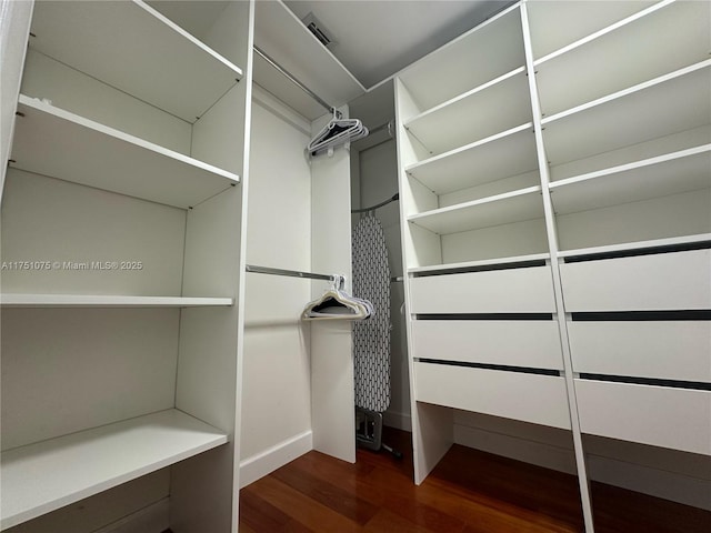 spacious closet with dark wood-style floors and visible vents