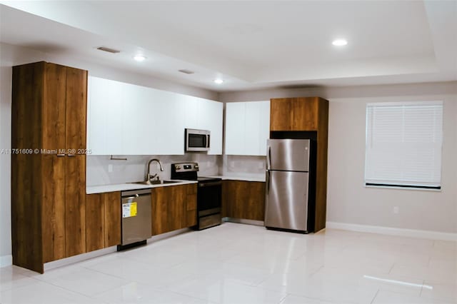 kitchen featuring a sink, white cabinets, stainless steel appliances, and light countertops