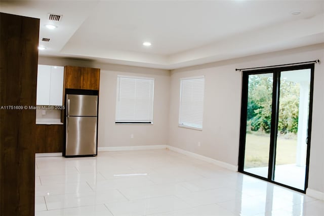 interior space featuring light tile patterned floors, a tray ceiling, recessed lighting, and baseboards