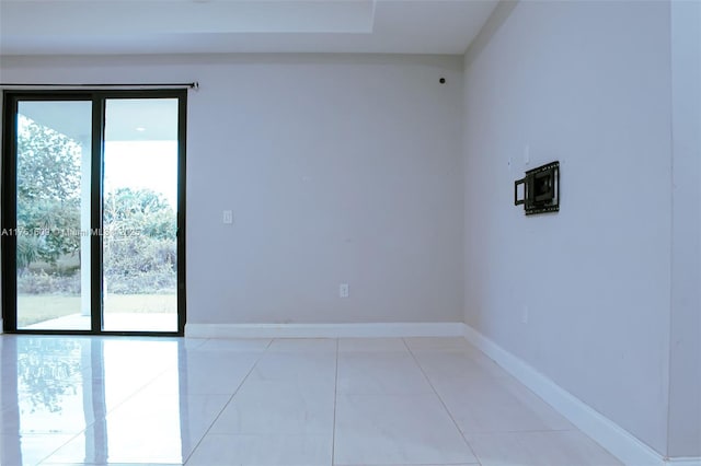 spare room with light tile patterned floors, baseboards, and a healthy amount of sunlight