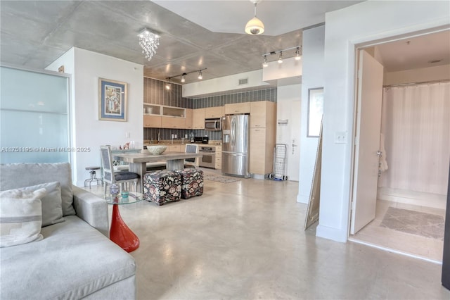 living room with concrete flooring, rail lighting, and visible vents