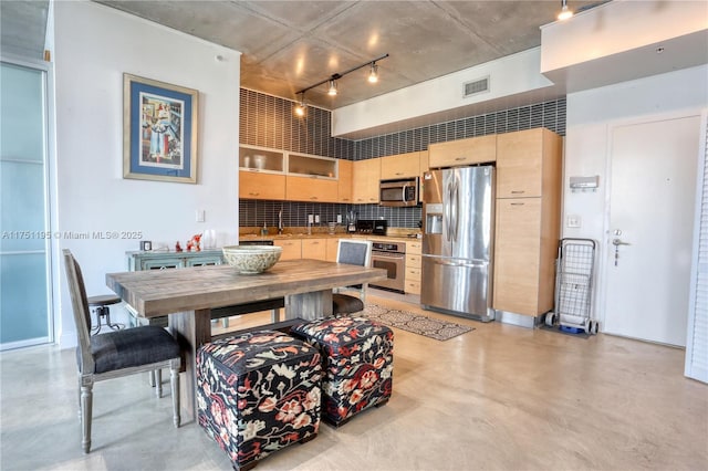 kitchen with light brown cabinets, visible vents, appliances with stainless steel finishes, tasteful backsplash, and finished concrete floors