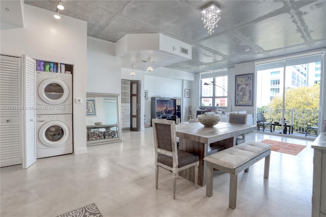 dining area with floor to ceiling windows, finished concrete flooring, stacked washer and dryer, visible vents, and a chandelier