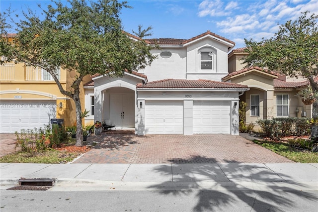 mediterranean / spanish-style home with a tiled roof, decorative driveway, and stucco siding