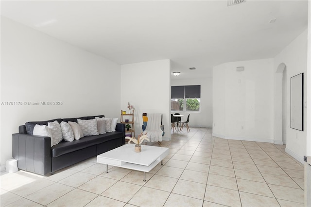 living area with arched walkways, light tile patterned flooring, and visible vents