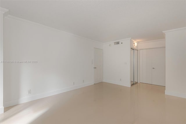 empty room with visible vents, crown molding, a textured ceiling, and baseboards