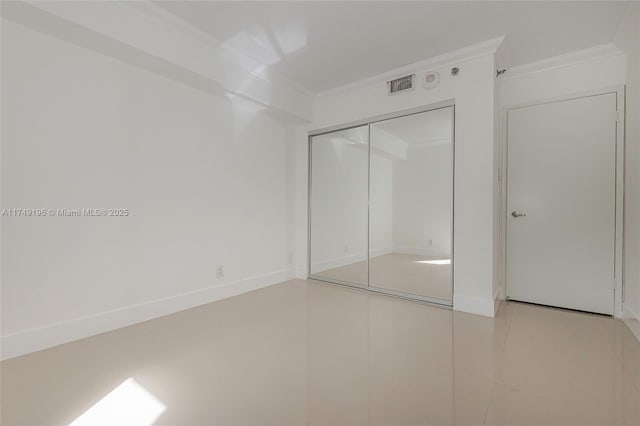 unfurnished bedroom with a closet, visible vents, crown molding, and baseboards