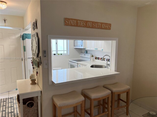 325 Ocean Dr Unit 308, Miami Beach, FL 33139 - kitchen featuring white appliances, a sink, light tile patterned floors, a breakfast bar, and light countertops