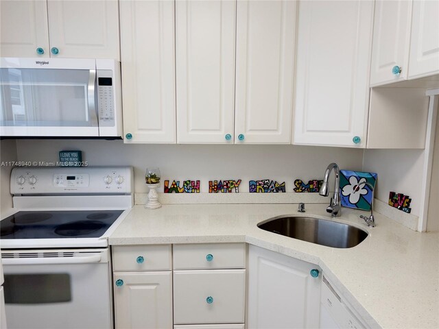 325 Ocean Dr Unit 308, Miami Beach, FL 33139 - kitchen with white appliances, a sink, white cabinets, and light countertops