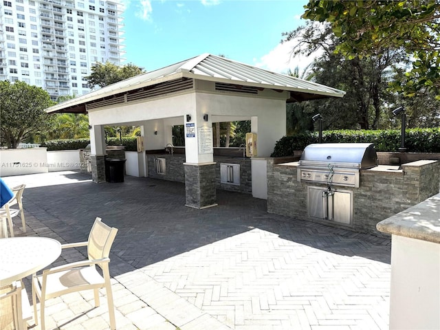 view of patio / terrace featuring exterior kitchen, a sink, a grill, and a gazebo