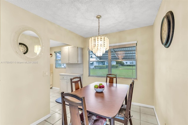 dining room with light tile patterned floors, baseboards, an inviting chandelier, and a textured ceiling